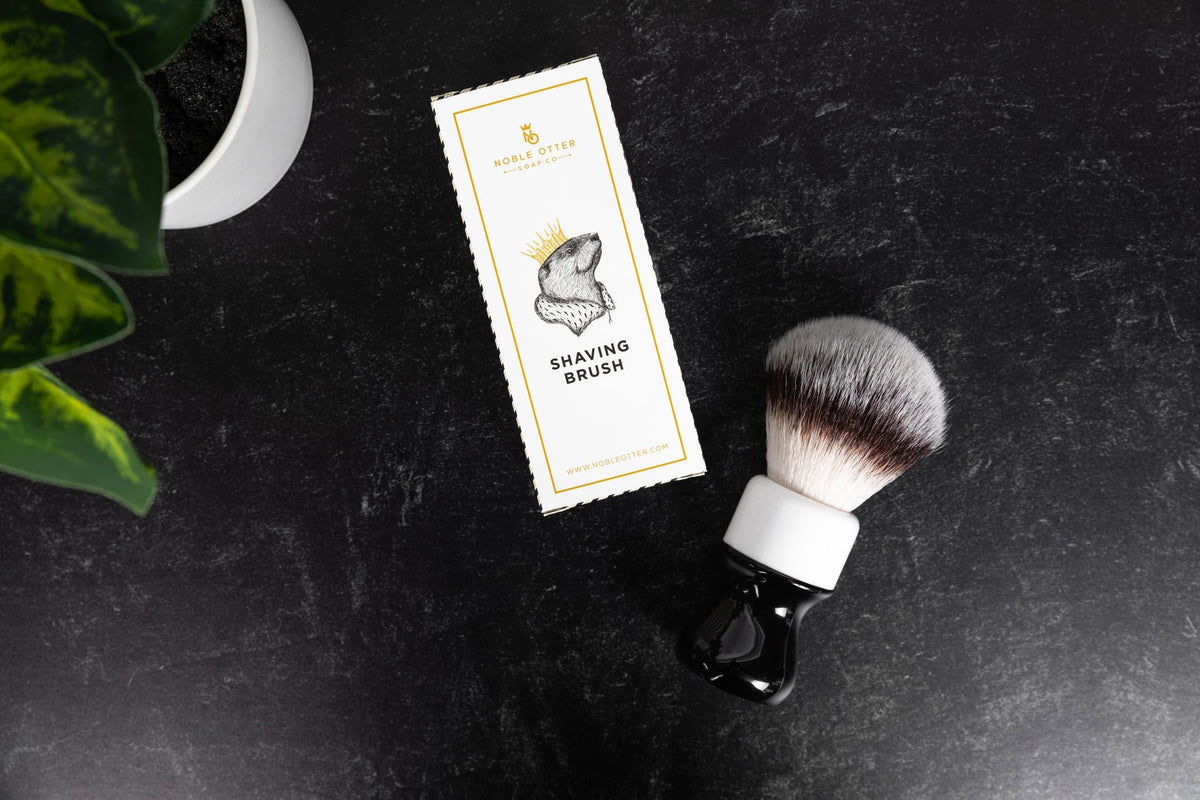 Noble Otter Soap Co. 26mm synthetic shaving brush with black and white handle, shown with branded white packaging box