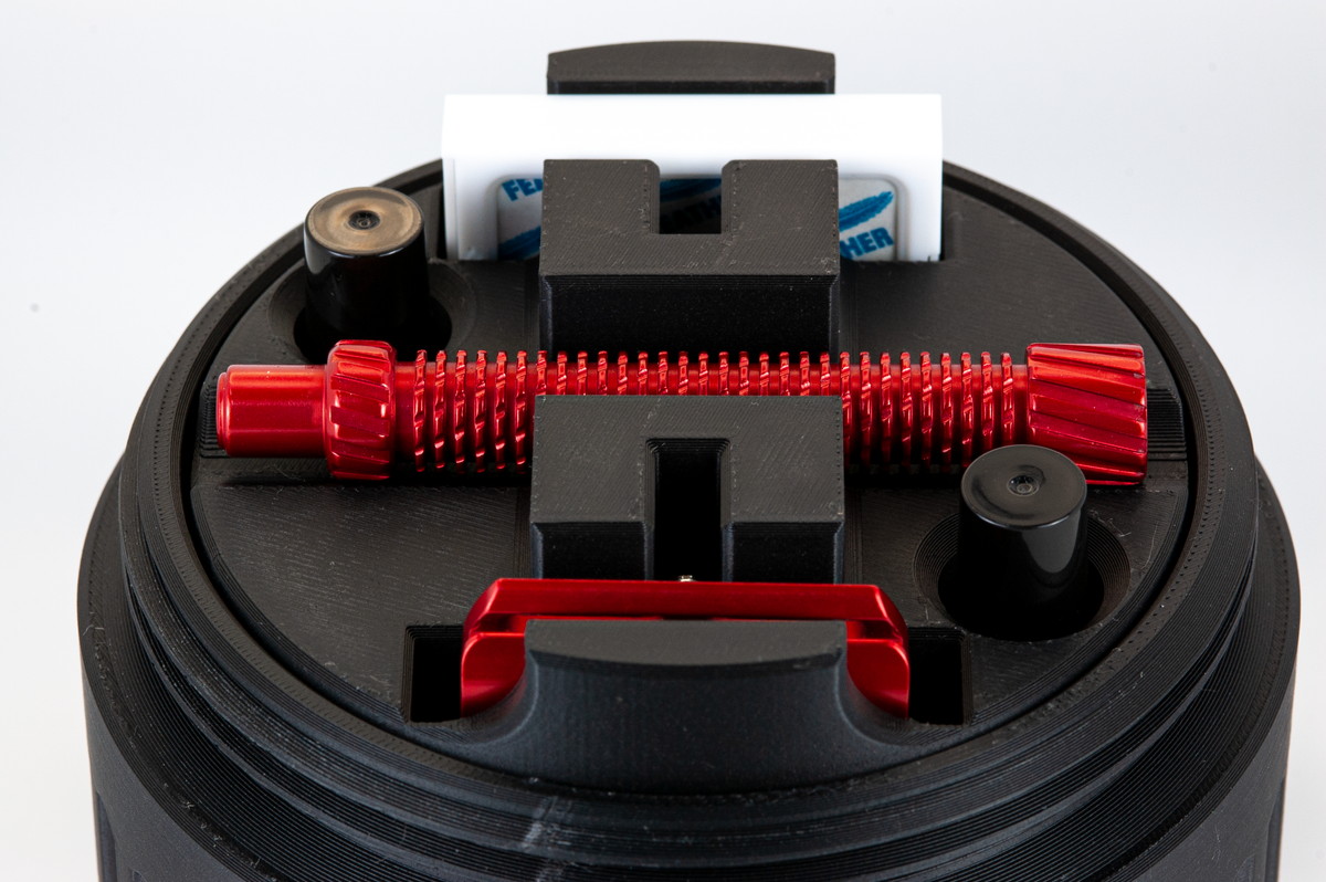 Closeup of the UFO insert showing a red razor, two atomizers, and a pack of feather blades stored in the insert.