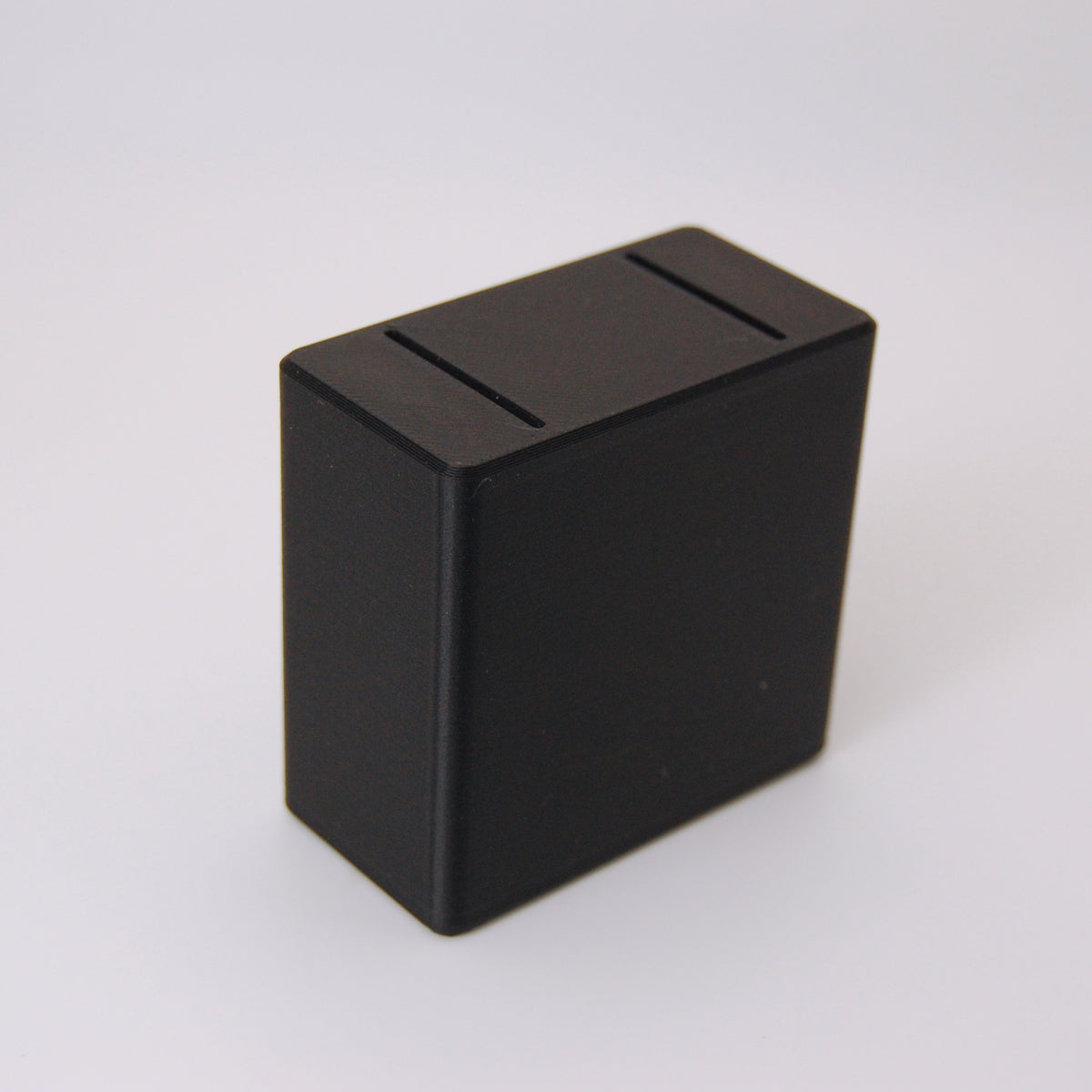 Black rectangular razor blade bank with two slots on top for used blade disposal, matte finish