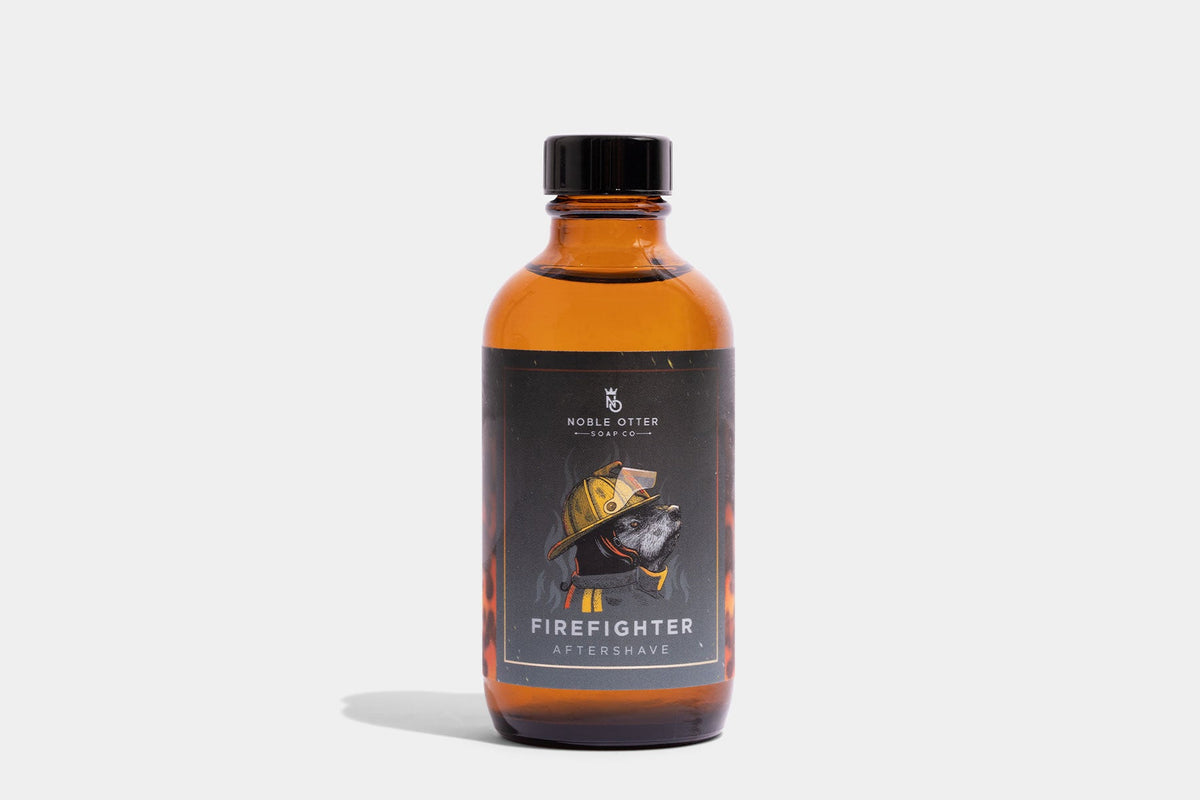 Noble Otter Soap Co Firefighter Aftershave in amber glass bottle with black cap, label showing otter in firefighter gear and flames