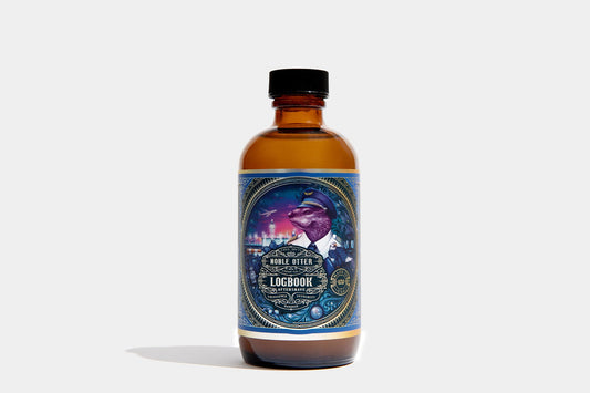 Noble Otter Logbook Aftershave in amber glass bottle with black cap, blue and gold label featuring an otter in pilot uniform