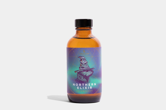 Noble Otter Northern Elixir Aftershave in amber glass bottle with black cap, purple and teal label with badger illustration