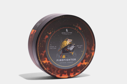 Noble Otter Firefighter Shave Soap 4oz round tub with dark label featuring an otter in firefighter gear surrounded by flames