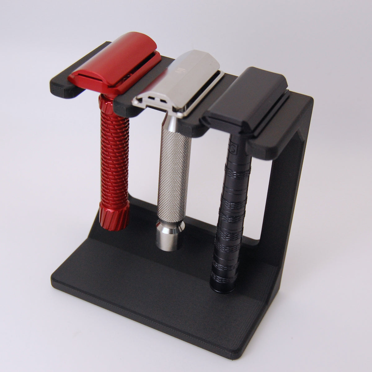 Three razors on a black stand against a white background