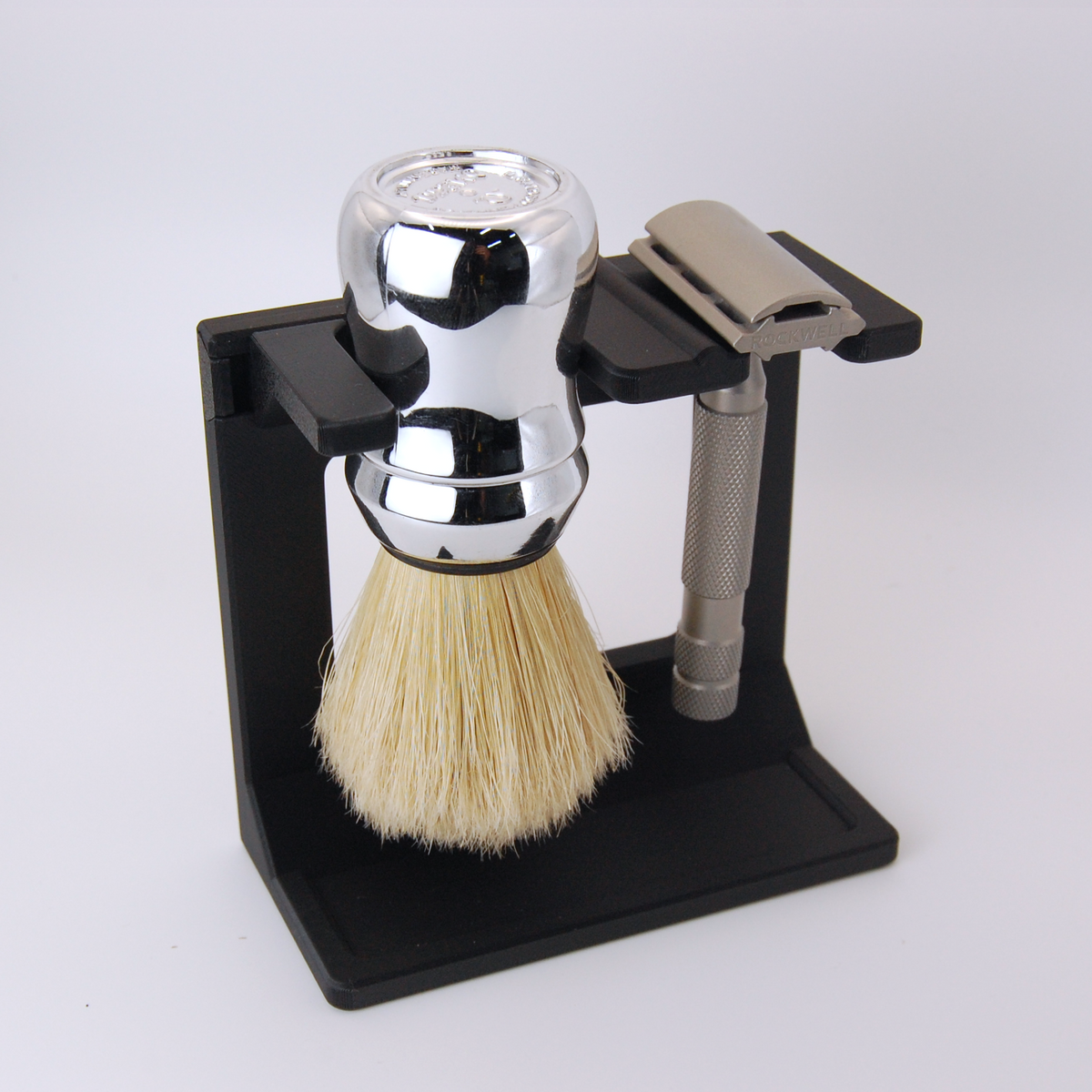 Shaving brush and razor on a black stand with a white background