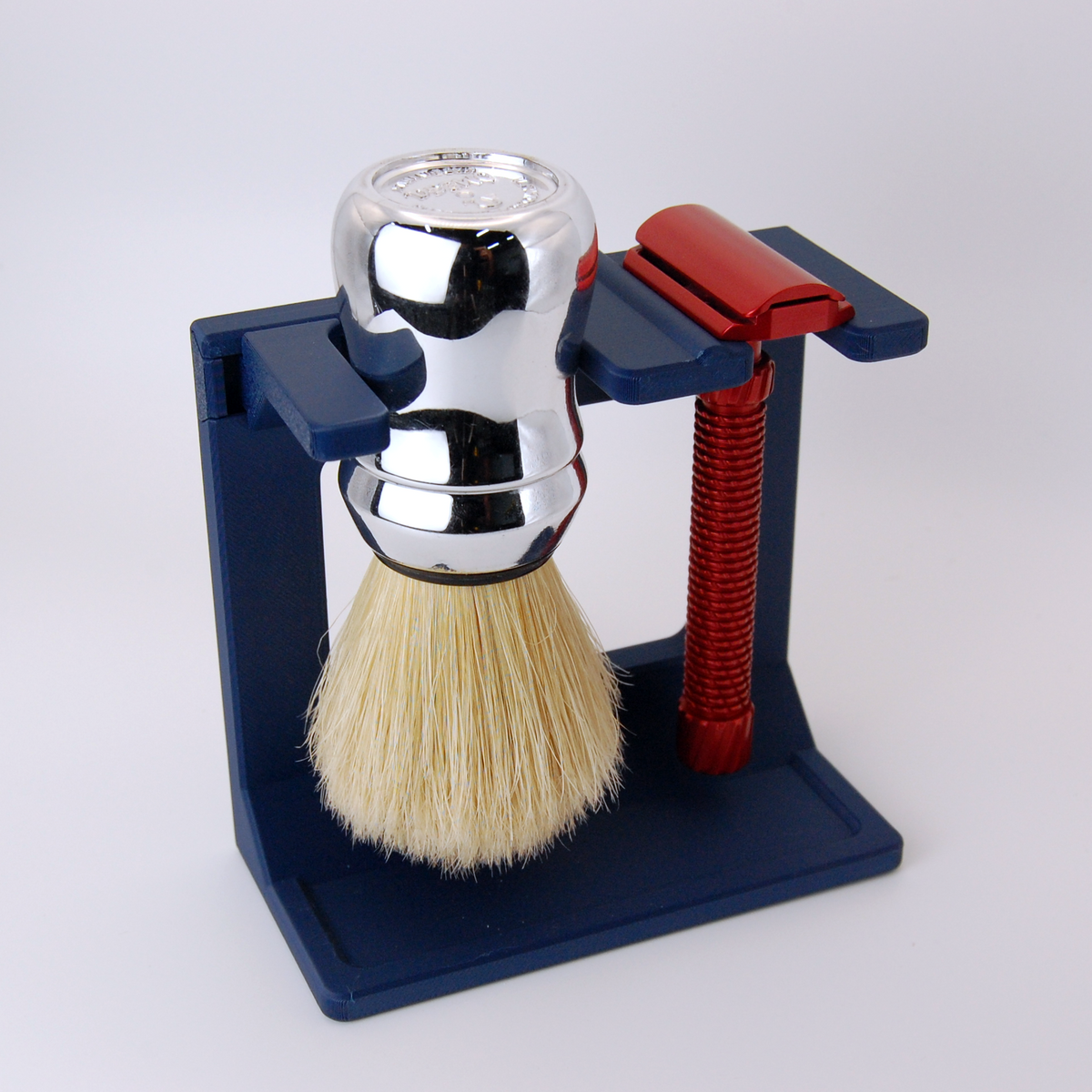 Navy Blue Shaving brush with stand and red handled razor  on a white background