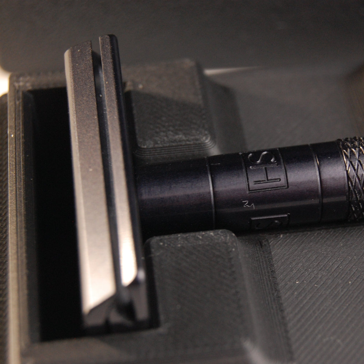 Black universal case with a black Henson AL13. Two feather blade boxes are stored alongside the razor.