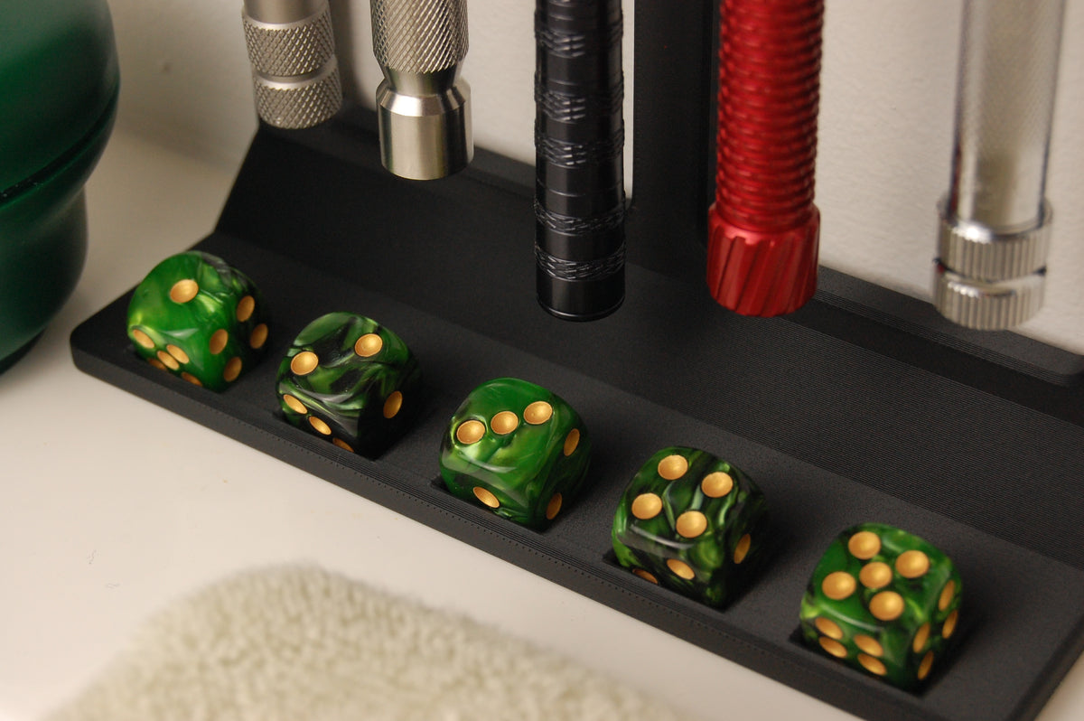 Black matte razor display stand holding multiple safety razors with a front channel storing five green marbled dice with gold pips
