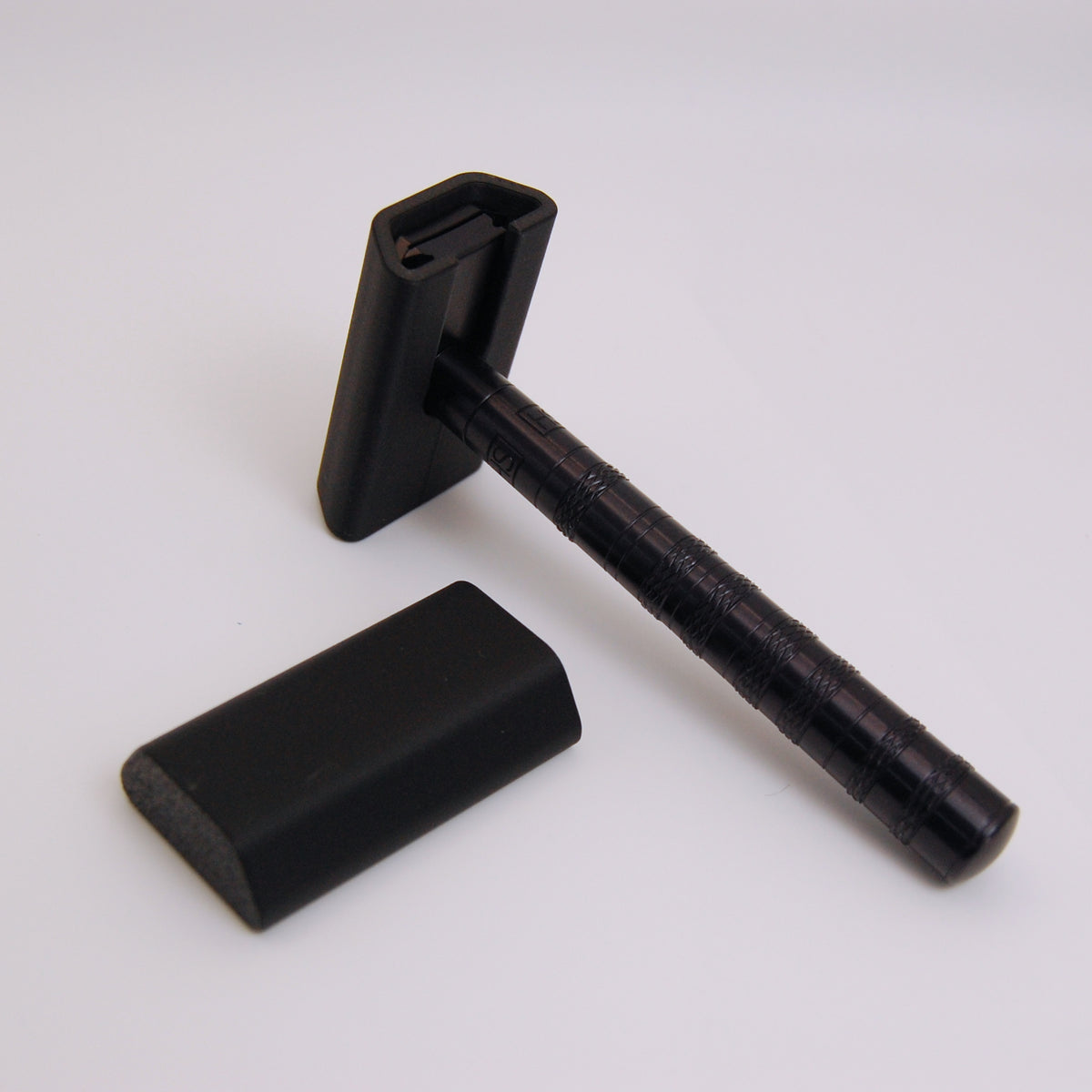 Black matte Henson razor travel cover shown fitted on an AL13 safety razor head, with a second cover resting beside it