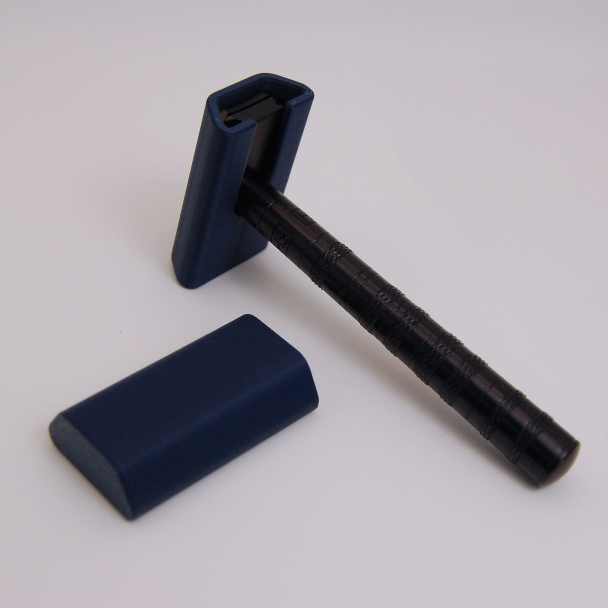 Dark navy blue snap-on travel cover for Henson AL13 safety razor, shown fitted on razor head with second cover beside it