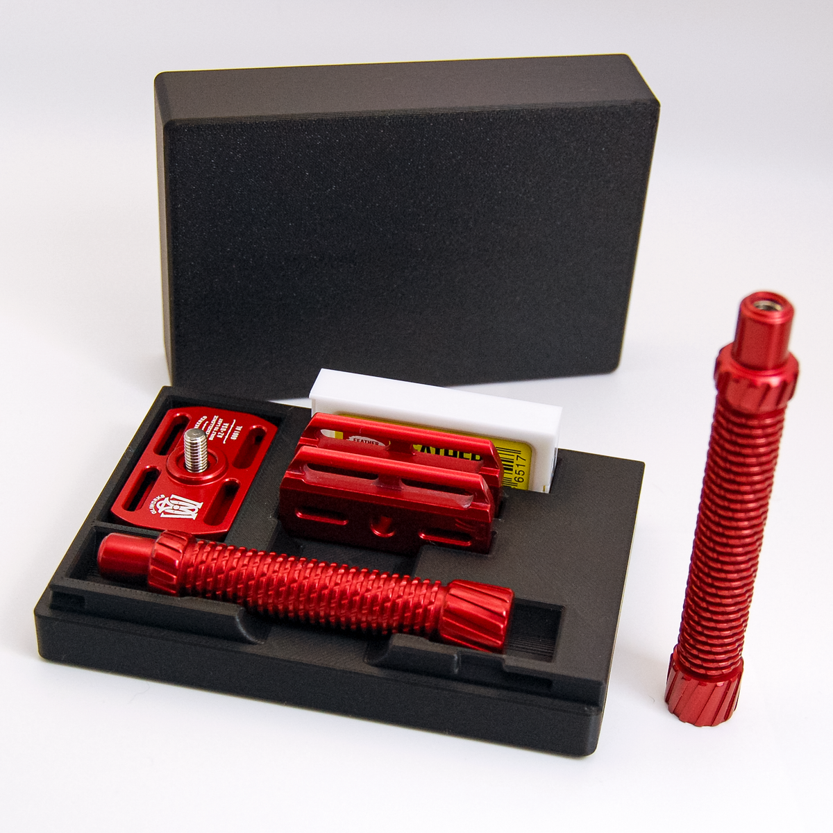 Black Oliworks M3teorite case open: red short handle, base plate, cap and blade box in their bays, long handle beside