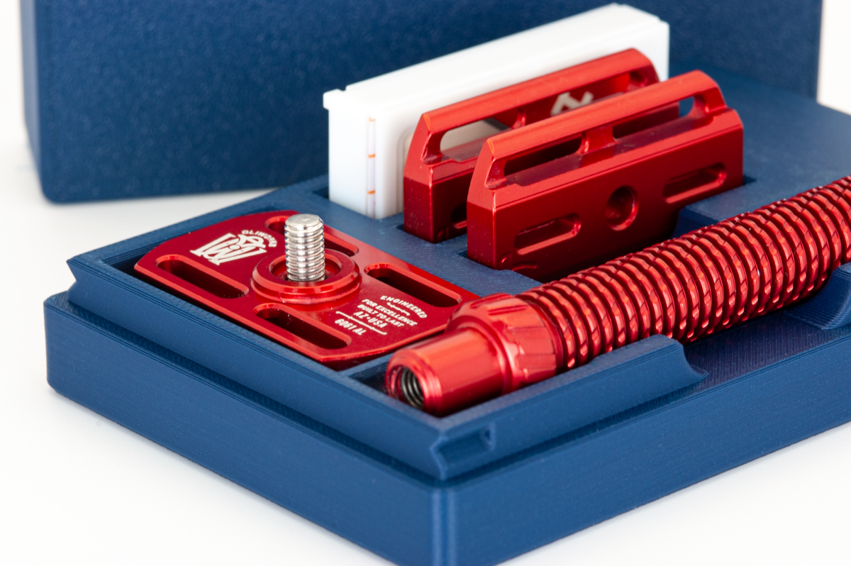 Angled close-up of the open Navy Blue Oliworks M3teorite case: red base plate, top caps and handle seated, blade box behind