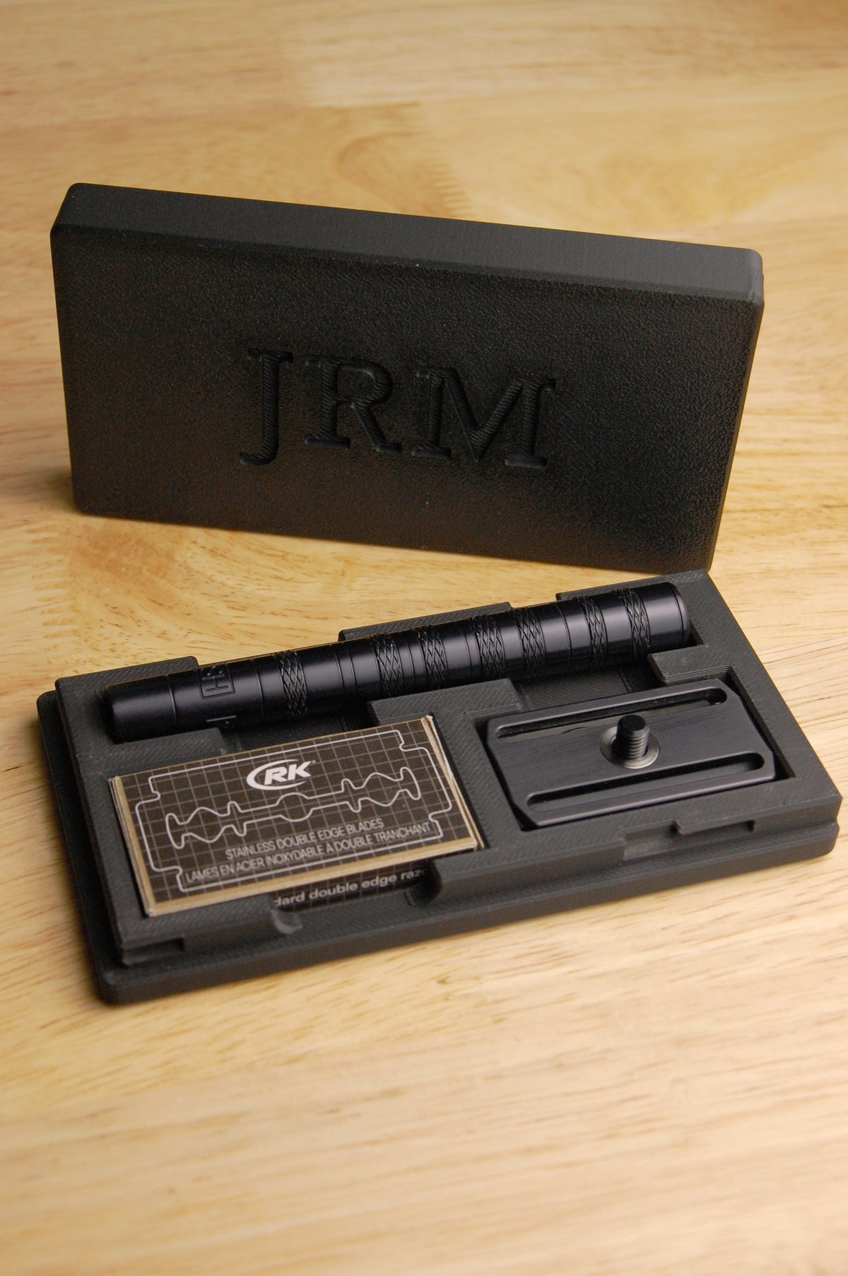 Henson Razor Travel Case Demo. Someone opens the case, takes apart the Henson Safety razor, puts the handle and razor head in the case, and then puts  box of razor blades in the case.  Finally they pick up the lid and place it on the base of the case then slide it closed.  