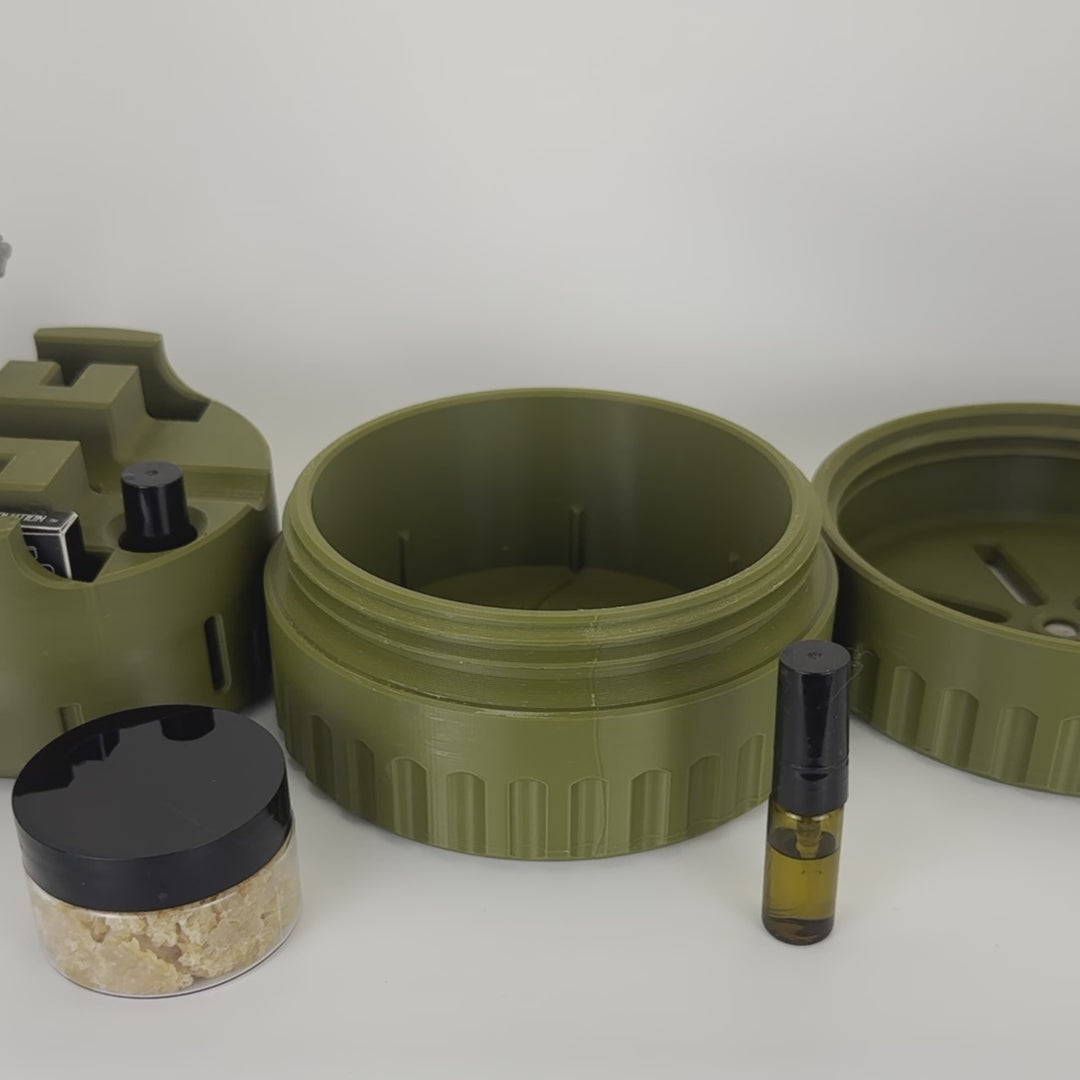 Demo video: a hand loads a silver safety razor into an army green UFO insert, with an atomizer and the lid alongside.