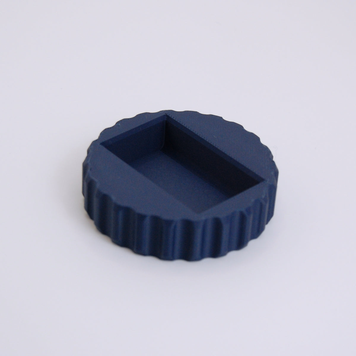 Navy blue round scalloped-edge razor blade change tool with rectangular recessed slot on top
