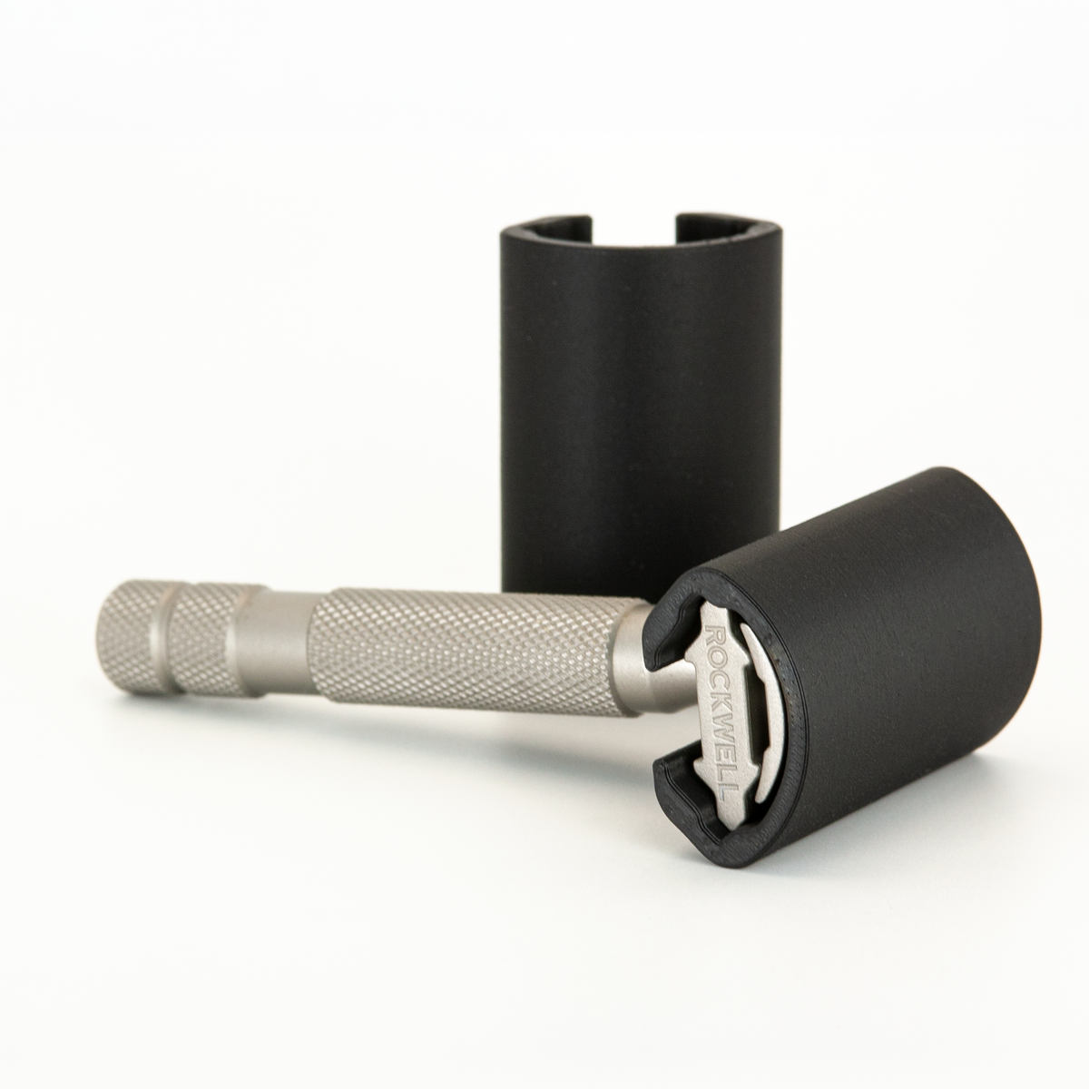 Black Rockwell travel cover slid over the head of a stainless Rockwell 6S, a second cover standing behind