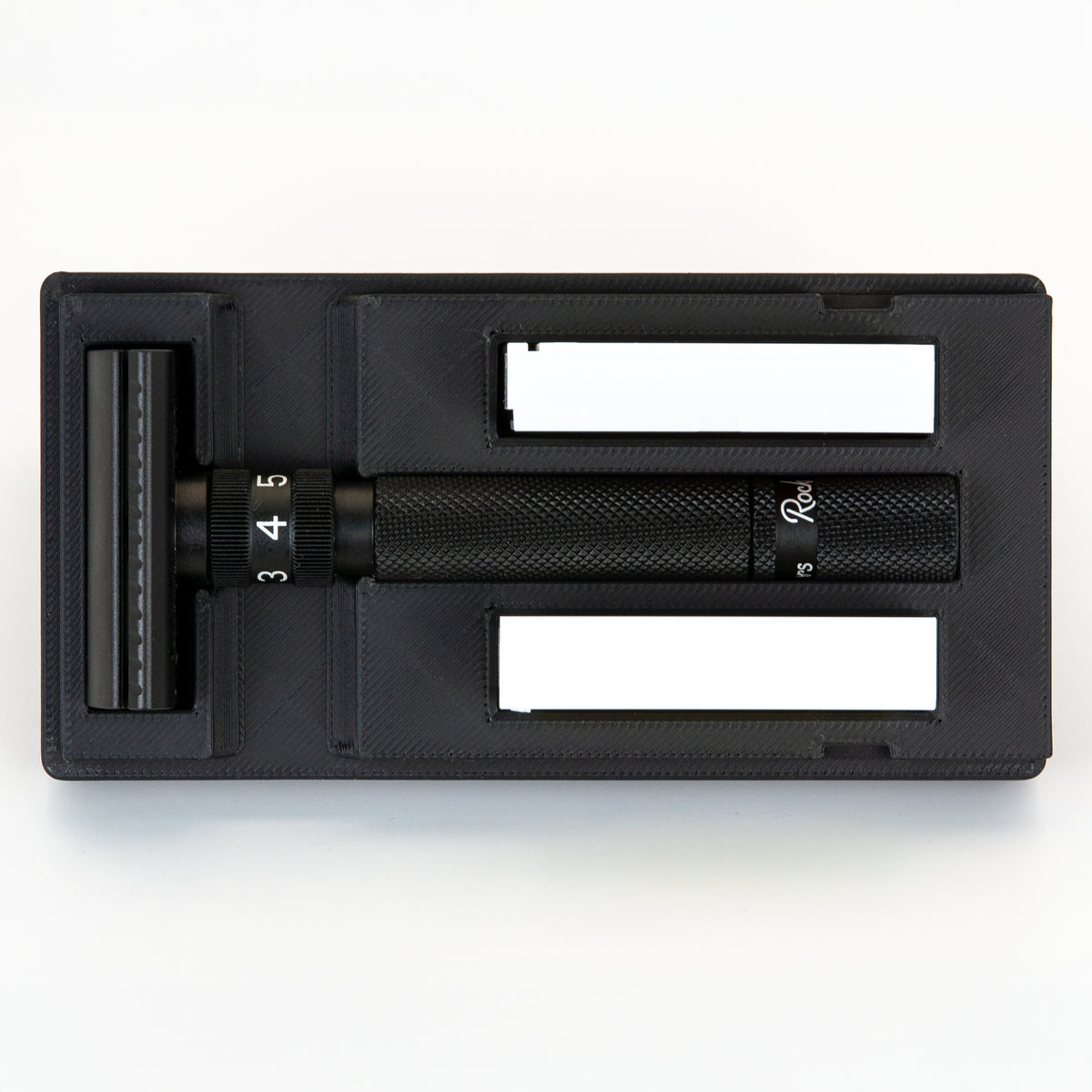 Open black Rockwell Setpoint razor travel case from above: Setpoint head, dial handle, and two blade boxes each in their own bay
