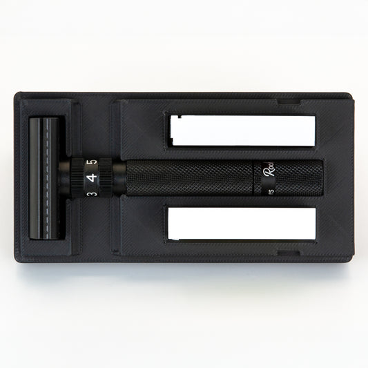 Open black Rockwell Setpoint razor travel case from above: Setpoint head, dial handle, and two blade boxes each in their own bay
