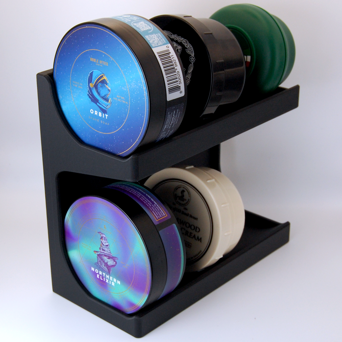 Black JRM Shave soap stand with soaps on both levels, sitting against a white background.